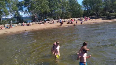 a group of children standing in the water at a beach at Geilo sentrumsnær leilighet in Geilo