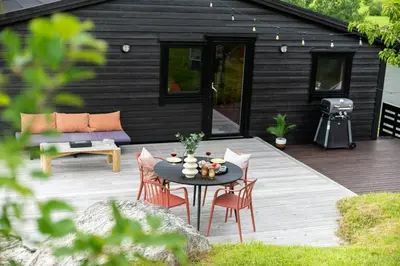 a patio with a table and chairs and a grill at Modern And Rustic Cabin With Fjord View In Samnanger in Årland