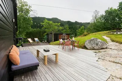 a wooden deck with a table and chairs on it at Modern And Rustic Cabin With Fjord View In Samnanger in Årland