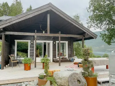 a house with a large wooden deck with plants at Cozy Modern Cabin In West Norway With View in Davik