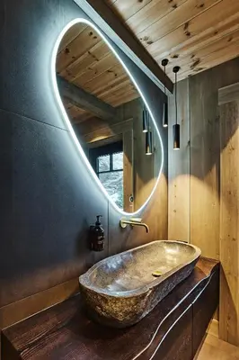 a bathroom with a large stone sink with a circular mirror at Luxury Cabin With Views in Stranda