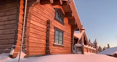 a log cabin in the snow with two windows at Cozy Log Cabin With A View Over Hedmarken in Løten