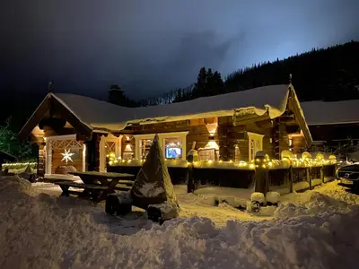a log cabin with lights in the snow at night at Luxury Log Cabin By Hardangervidda in Uvdal