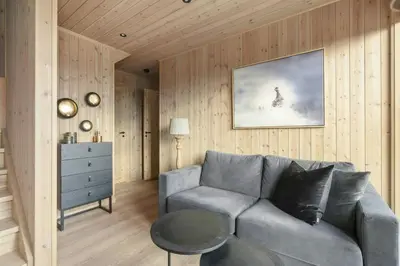 a living room with a gray couch and a dresser at Norefjell Cottage With Sauna And Whirlpool in Noresund