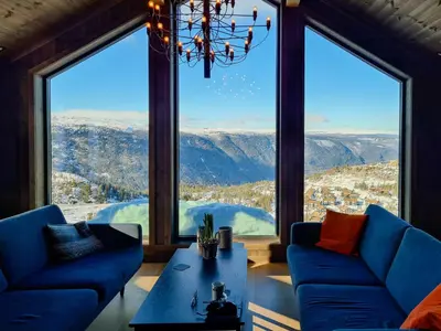 a living room with blue couches and a large window at Luxury Mountain Home With View On Gaustablikk in Rjukan