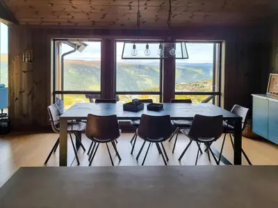 a dining room table with chairs and a large window at Luxury Mountain Home With View On Gaustablikk in Rjukan