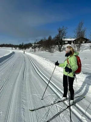 a woman is cross country skiing on a snow covered road at Large Log Cabin, Ski Fun Near Dagali in Dagali