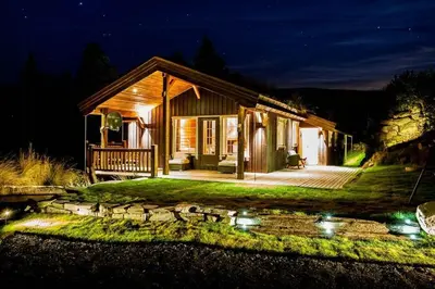 a house at night with a pond in front of it at Cozy Cabin In Uvdal With Jacuzzi And Sauna in Uvdal
