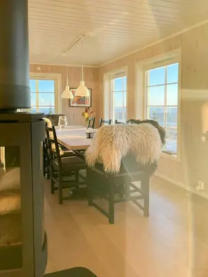 a dining room with a table with furry seats and windows at Modern Mountain Cabin With Panoramic Views in Sjusjøen