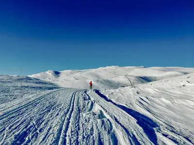 a person is walking down a snow covered mountain at Charming Cabin Overlooking Vegglifjell in Kravikfjord
