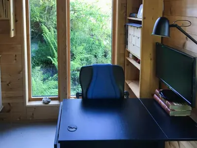 a desk with a chair in a room with a window at Charming Artist's Cabin With Sea View Near Bergen in Straume