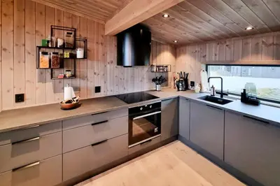 a kitchen with stainless steel appliances and wooden walls at Stylish Modern Cabin In Charming Kvitfjell in Favang