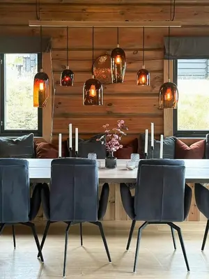 a dining room with a table with chairs and lights at Modern And Spacious Cabin At Mosetertoppen in Øyer