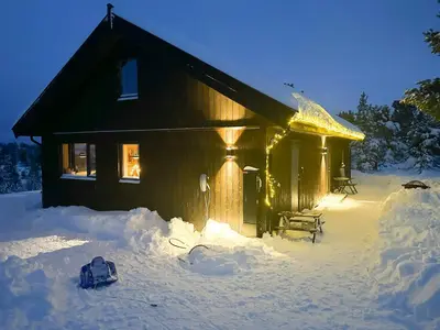 a house covered in snow with lights on it at Modern Mountain Home At Nerskogen, Trollheimen in Nerskogen