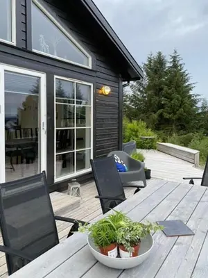 a wooden table with chairs and plants on a deck at Charming Cabin With Archipelago Views In Sogn in Ånneland