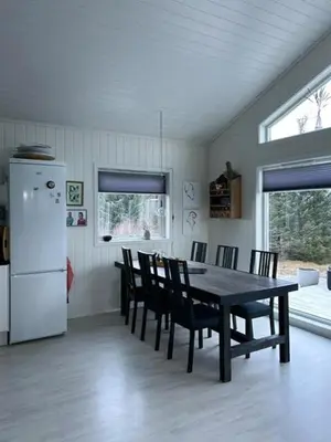 a kitchen with a table and chairs and a refrigerator at Charming Cabin With Archipelago Views In Sogn in Ånneland