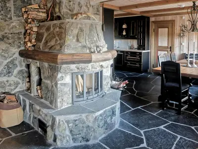 a stone fireplace in the middle of a room with a table at Large Cabin By Farhovdtjønn In Rauland in Rauland