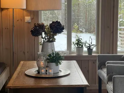 a table with flowers in a room with a window at Family Cabin With Panoramic View Near Vikerfjellet in Hønefoss