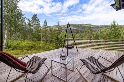 a porch with two chairs and a table on a deck at Family Cabin With Panoramic View Near Vikerfjellet in Hønefoss
