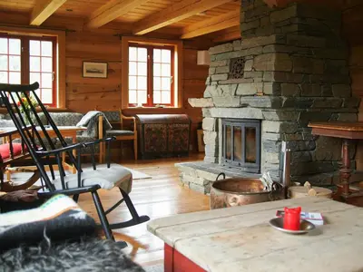 a living room with a stone fireplace in a cabin at Cabin With Wooden Interior By Lake Tinnsjøen in Atra
