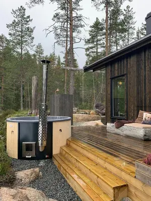 a hot tub sitting on a deck next to a cabin at Enjoy Simple Cabin Life In Nature in Kongsberg