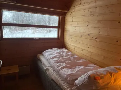a bedroom with a bed in a wooden room with a window at Relaxing Mountain Cabin With Panoramic Views in Beitostøl
