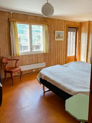 a bedroom with a bed and a chair and windows at Fantastic Charming Cabin By Tinnsjøen in Austbygdi