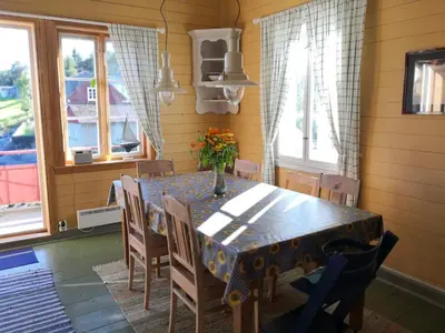 a dining room with a table and chairs and windows at Charming sea house with sauna and private jetty in Ølve