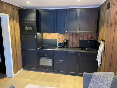 a kitchen with dark blue cabinets in a room at Hafjell Alpinlandsby Apartment 43 in Hafjell