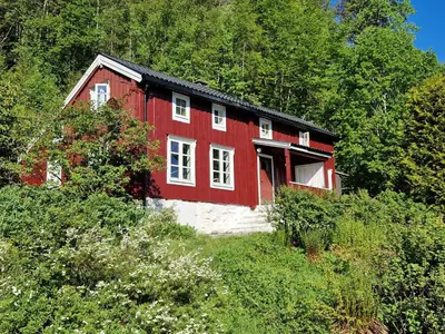 a red and white house on the side of a hill at Old Fishermans Home By Mjosundet In Aure in Valen