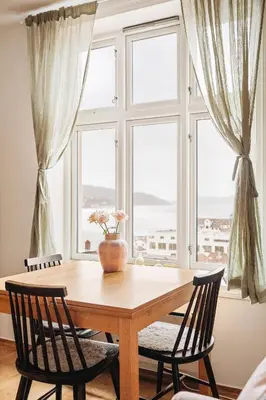 a table with chairs and a vase on it in front of a window at Unique apartment-Romantic Street-Easy Check-In in Bergen