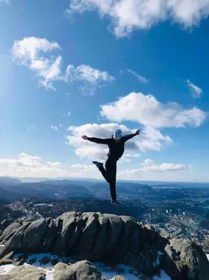a person jumping in the air on top of a mountain at In the heart of Bergen in Bergen