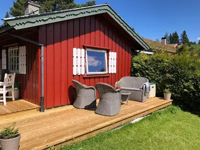 a red building with wicker chairs on a deck at Cozy cabin 1,5 hours from Oslo in Hamar