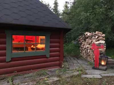 a red cabin with a pile of fire wood next to a window at Cozy cabin 1,5 hours from Oslo in Hamar