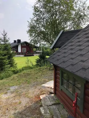 a house on a hill next to a house with a yard at Cabin with large outdoor area in Hamar