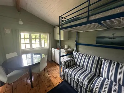 a living room with a couch and a table and a bunk bed at Turifoss Camping Cabin 2 in Svedjan