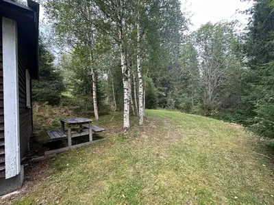 a picnic table in a field next to a house at Turifoss Camping Cabin 2 in Svedjan