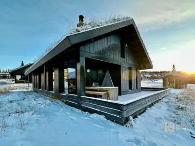 a person standing on top of a house in the snow at Modern cabin Hafjell high standard ski-in out in Hafjell