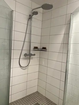 a shower in a white tiled bathroom at Attraktiv utsiktsleilighet in Ranheim