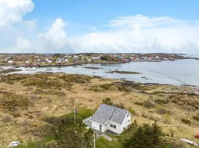a white house on a hill next to a body of water at Idyllisk perle ved sjøen! in Frøya