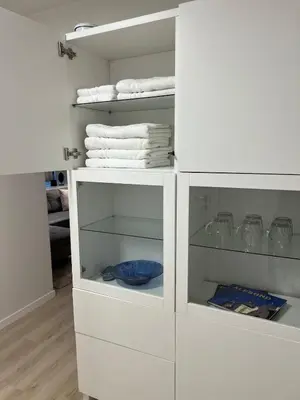 a white cabinet with glass shelves and towels at Mint Apartment in Ålesund