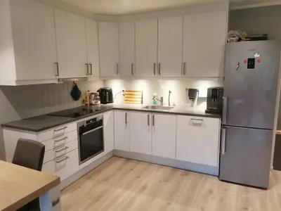 a kitchen with white cabinets and a stainless steel refrigerator at Lovely apartment with stunning views in Torset