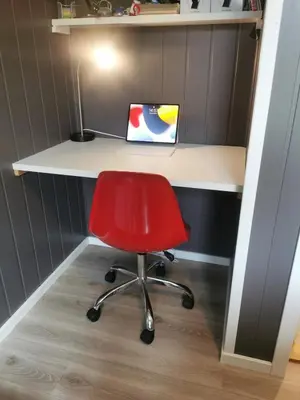 a red chair sitting in front of a desk with a laptop at Lovely apartment with stunning views in Torset