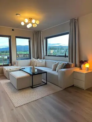 a living room with a white couch and large windows at Delicate and new apartment in quiet surroundings in Trondheim