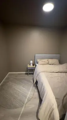 a bedroom with a bed and a table with a rug at Delicate and new apartment in quiet surroundings in Trondheim