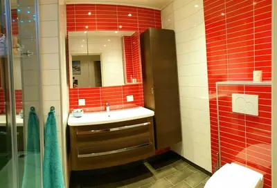 a red tiled bathroom with a sink and a mirror at Spacious house close to Ski World Championship in Trondheim