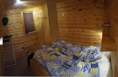 a bedroom with a bed and a wooden wall at Cozy cabin centrally located in Hovden in Hovden