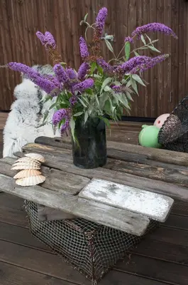 a vase with purple flowers on a wooden table at Modern seaside holiday home in Bømlo