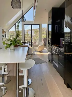 a kitchen and living room with a white table and chairs at Modern seaside holiday home in Bømlo