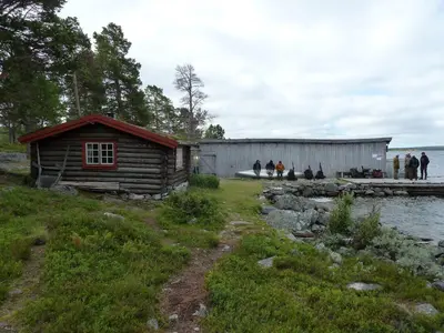 a small wooden cabin next to a body of water at Family cabin by the lake at Haugen, Femundsmarka in Elga